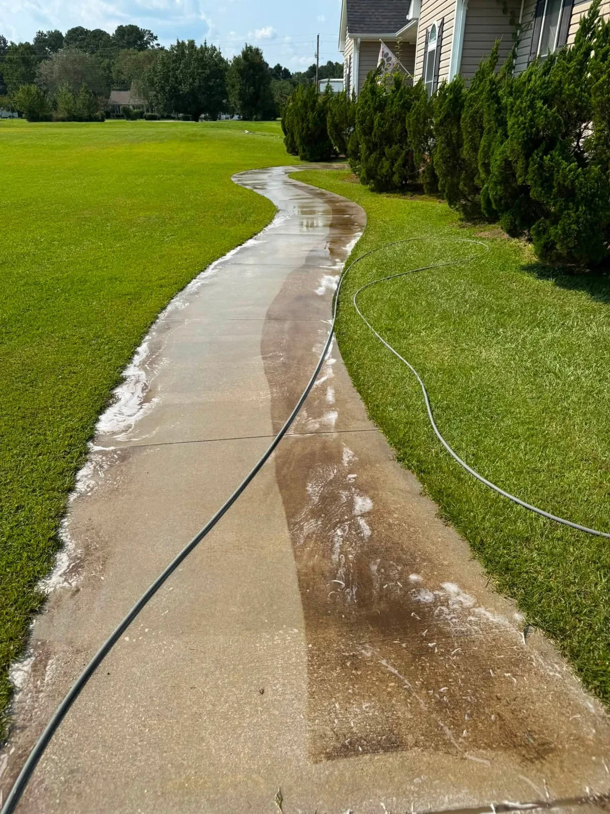Half-cleaned sidewalk showing dramatic difference between dirty and clean concrete